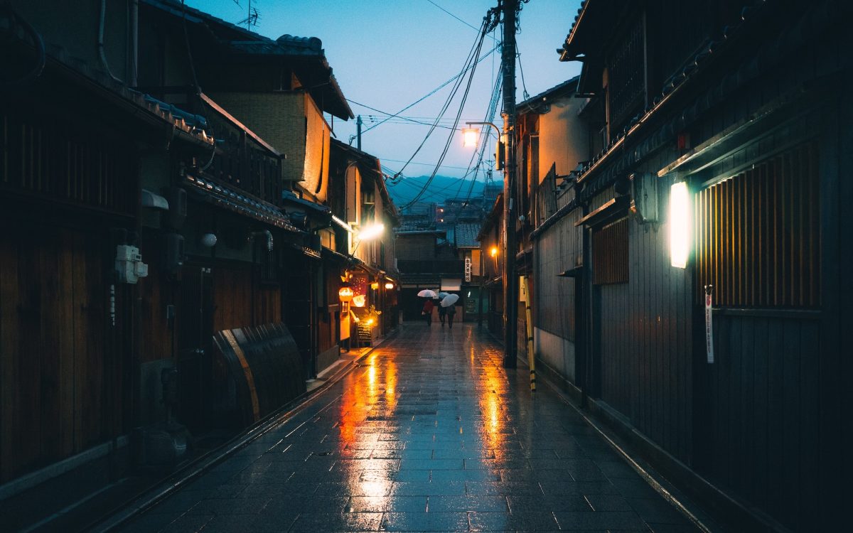 Horizontal shot of an empty pathway between houses in Japan during the nighttime while raining