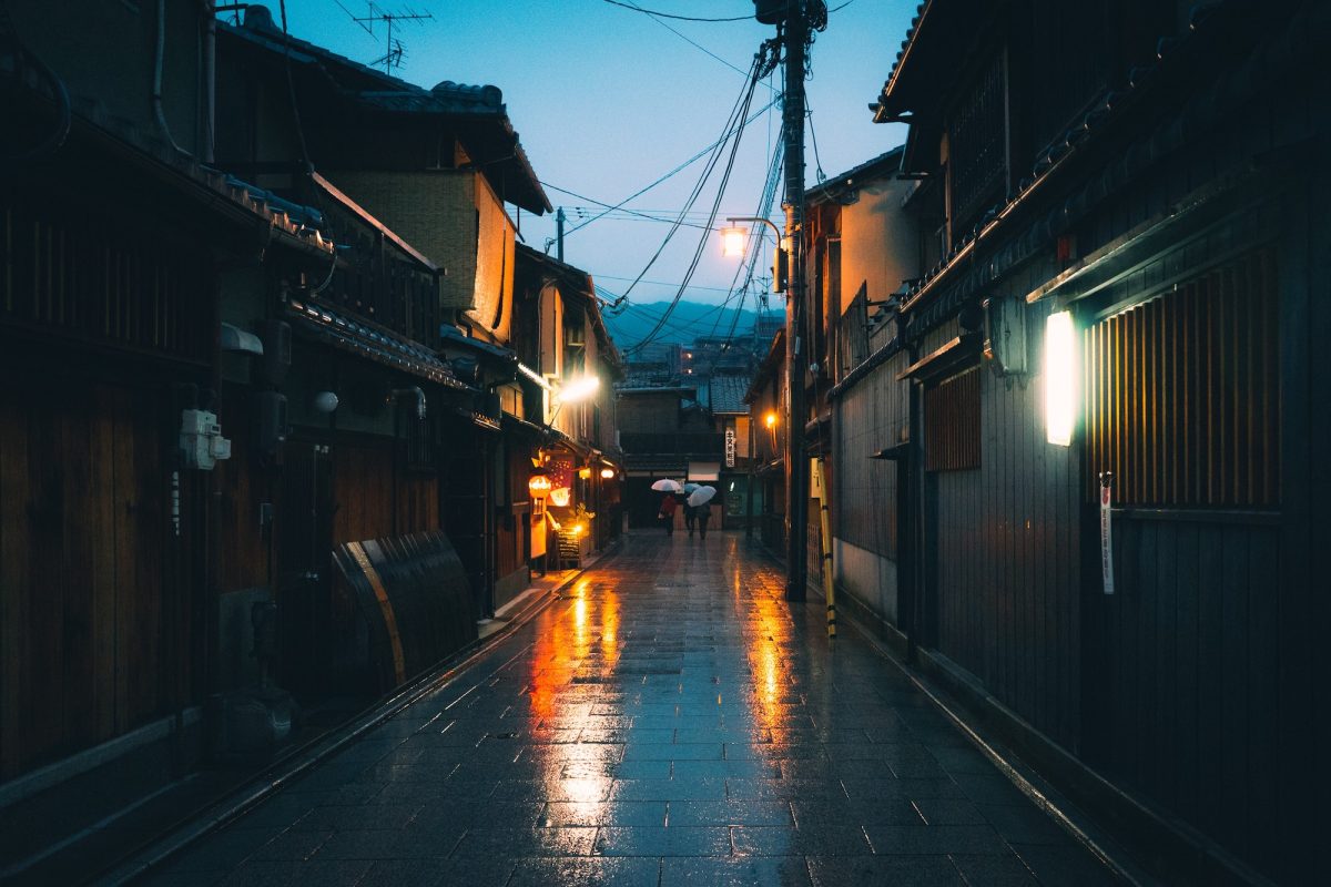 Horizontal shot of an empty pathway between houses in Japan during the nighttime while raining
